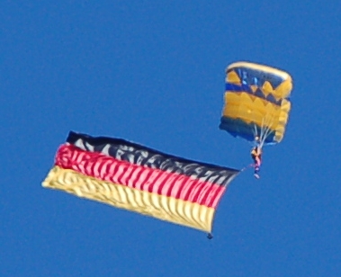 Ein Fallschirmspringer mit Deutschlandfahne im Schlepptau über Holtenau